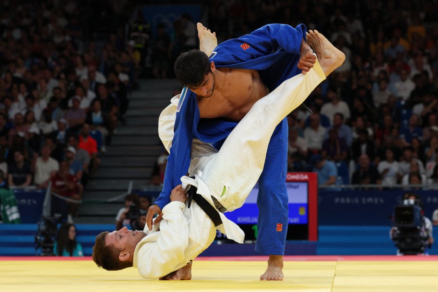 Canada's Arthur Margelidon and Tajikistan's Behruzi Khojazoda (Blue) compete in the judo men's -73kg round of 32 round bout of the Paris 2024 Olympic Games.