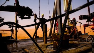 A Repsol Oil Operations oil drilling rig pounds into the desert searching through thousands of feet for and oil reserve in El-Sharara, Libya.