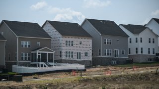 A house under construction is seen between completed houses in a new development in Brambleton, Virginia on August 14, 2024.