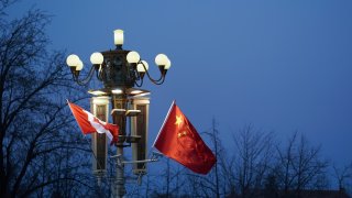 BEIJING, CHINA – DECEMBER 04:  China and Canada flag is displayed in front of the Forbidden City on December 4, 2017 in Beijing, China.