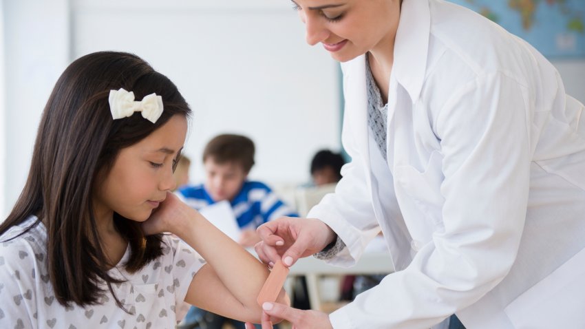 School nurse putting band aid on child's elbow