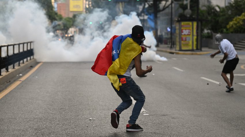 A demonstrator throws a stone to police officers during a protest against Nicolas Maduro.