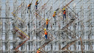 Laborers work at a coastal road project construction site in Mumbai on January 12, 2022.