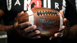 Phillip Laster Sr. holds a football in Brandon, Miss., Tuesday, Aug. 27, 2024, signed by teammates of his son Phillip Laster Jr., that was given to him on senior night after his passing.