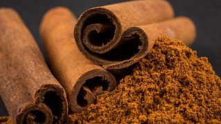 Cinnamon sticks with cinnamon powder on stone plate background