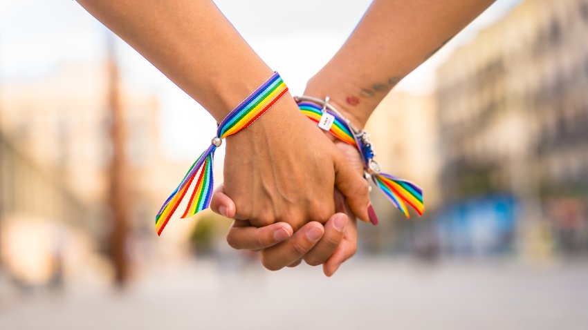 Two hands with rainbow bracelets holding