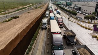 Aerial view of cargo trucks lining up to cross to the United States near the US-Mexico border at Otay Mesa crossing port in Tijuana, Mexico.