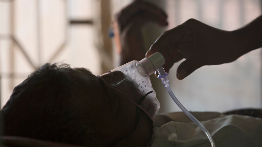 A relative adjusts the oxygen mask of a tuberculosis patient at a TB hospital.