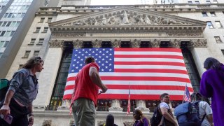 Pedestrians walk in front of the New York Stock Exchange (NYSE) decorated with a giant national flag of the United States on November 6, 2024 in New York City.