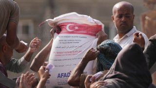 Palestinians gather to receive bags of flour distributed by UNRWA, the U.N. agency helping Palestinian refugees, in Deir al Balah, central Gaza Strip, Saturday, Nov. 2, 2024.