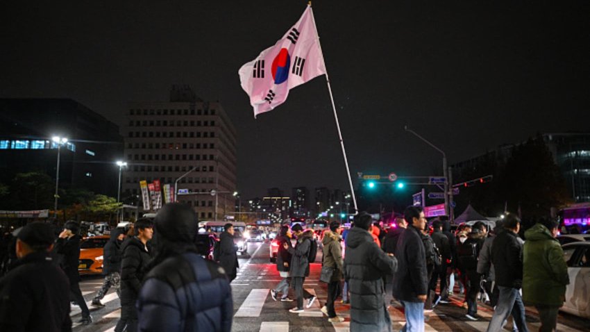 A man holds the South Korea flag outside the National Assembly in Seoul on December 4, 2024, after President Yoon Suk Yeol declared emergency martial law. South Korea’s President Yoon Suk Yeol on December 3 declared emergency martial law, saying the step was necessary to protect the country from “communist forces” amid parliamentary wrangling over a budget bill. 