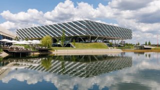 The “Arena” office building at the headquarters of the sporting goods manufacturer adidas AG is reflected in an artificial lake.