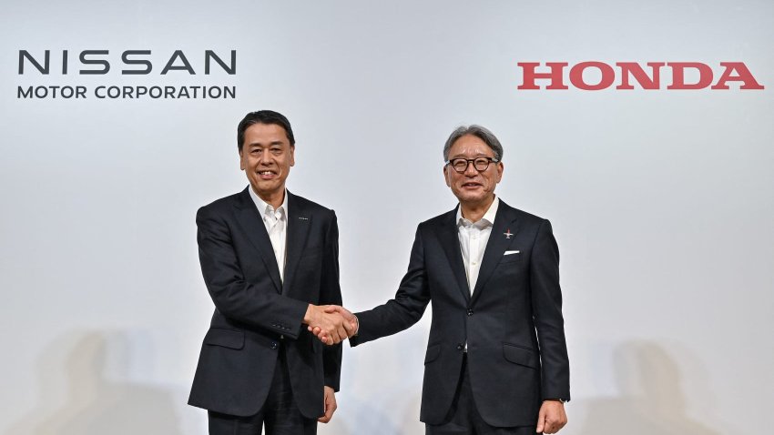 Makoto Uchida (L), president and CEO of Japanese auto maker Nissan, shakes hands with Toshihiro Mibe (R), director, president and representative executive officer of auto maker Honda, following a press conference in Tokyo on August 1, 2024. 