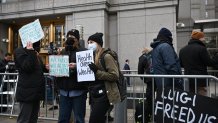 People hold signs outside the Federal Court building in New York as Luigi Mangione, the suspect in the United Healthcare CEO killing has waived extradition on December 19, 2024. Mangione, 26, is accused of shooting UnitedHealthcare chief executive Brian Thompson on a Manhattan street on December 4, triggering a nationwide manhunt that ended last week when he was spotted at a Pennsylvania McDonald's. The former data engineer remains jailed in that state as he fights efforts to extradite him to New York to face charges there over the killing. (Photo by ANGELA WEISS / AFP) (Photo by ANGELA WEISS/AFP via Getty Images)