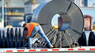 A truck driver chains down a roll of steel to his flatbed at the NUCOR Steel Gallatin plant in Ghent, Ky.