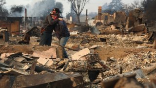 Khaled Fouad (L) and Mimi Laine (R) embrace as they inspect a family member’s property that was destroyed by Eaton Fire on Jan. 9, 2025 in Altadena, California.