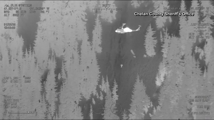 Infrared footage of a man being airlifted by a helicopter.