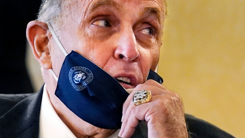 FILE — Former New York Mayor Rudy Giuliani, wearing a New York Yankees championship ring, pulls his face mask down to speak to an aide during a press conference at the Women's Republican Club, Sept. 16, 2020, in New York.