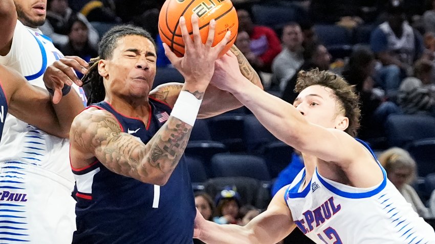 UConn guard Solo Ball, left, drives to the basket against DePaul guard Jacob Meyer, right, and forward NJ Benson during the first half of an NCAA college basketball game in Chicago, Wednesday, Jan. 1, 2025.