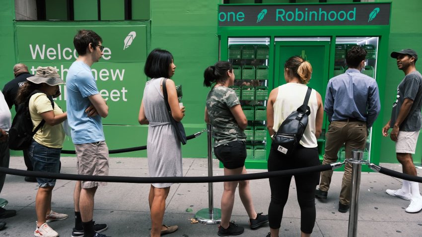 People wait in line for T-shirts at a pop-up kiosk for the online brokerage Robinhood along Wall Street after the company went public with an initial public offering earlier in the day on July 29, 2021 in New York City.