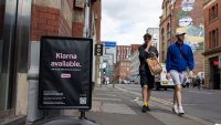 Pedestrians walk by an advertisement for Klarna.