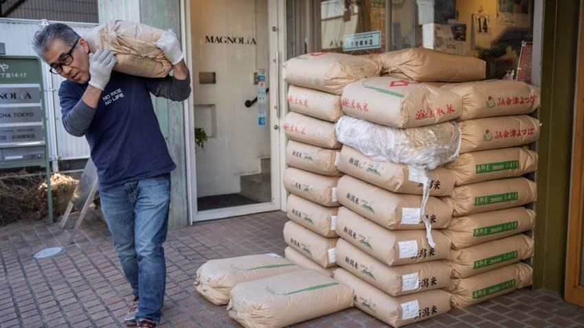 The owner of rice shop Tadao Koike carries a bag of rice at his shop in Tokyo on February 14, 2025. 