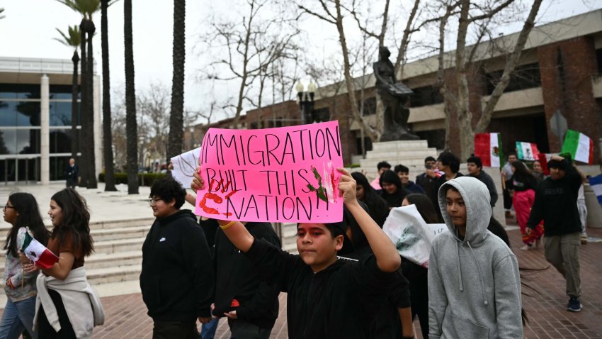 Students from Orange County Educational Arts Academy middle school hold placards in support of migrants