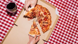 Top view of friends eating pepperoni pizza and drinking wine