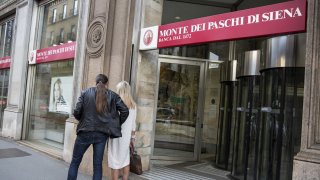 Pedestrians walk outside a Banca Monte dei Paschi di Siena SpA bank branch in Milan, Italy.