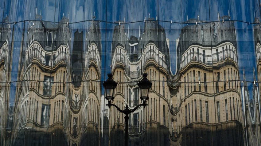 Haussmann architecture buildings are reflected on the facade of Samaritaine department store in central Paris on October 10, 2023.