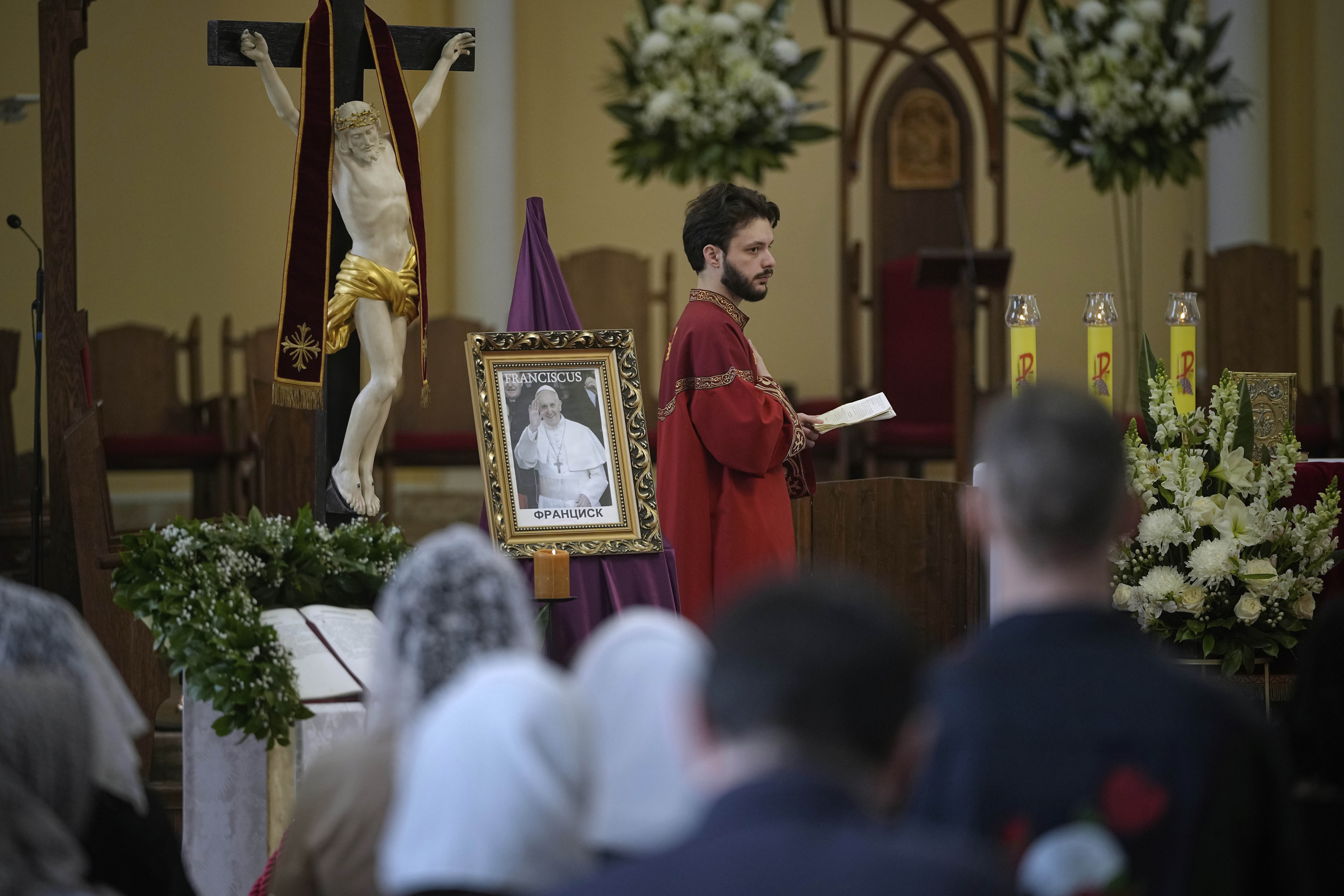 Parishioners attend a service sitting in front of a photo of the late Pope Francis after the news of his death at the Cathedral of the Immaculate Conception in Moscow, Russia, Monday, April 21, 2025.