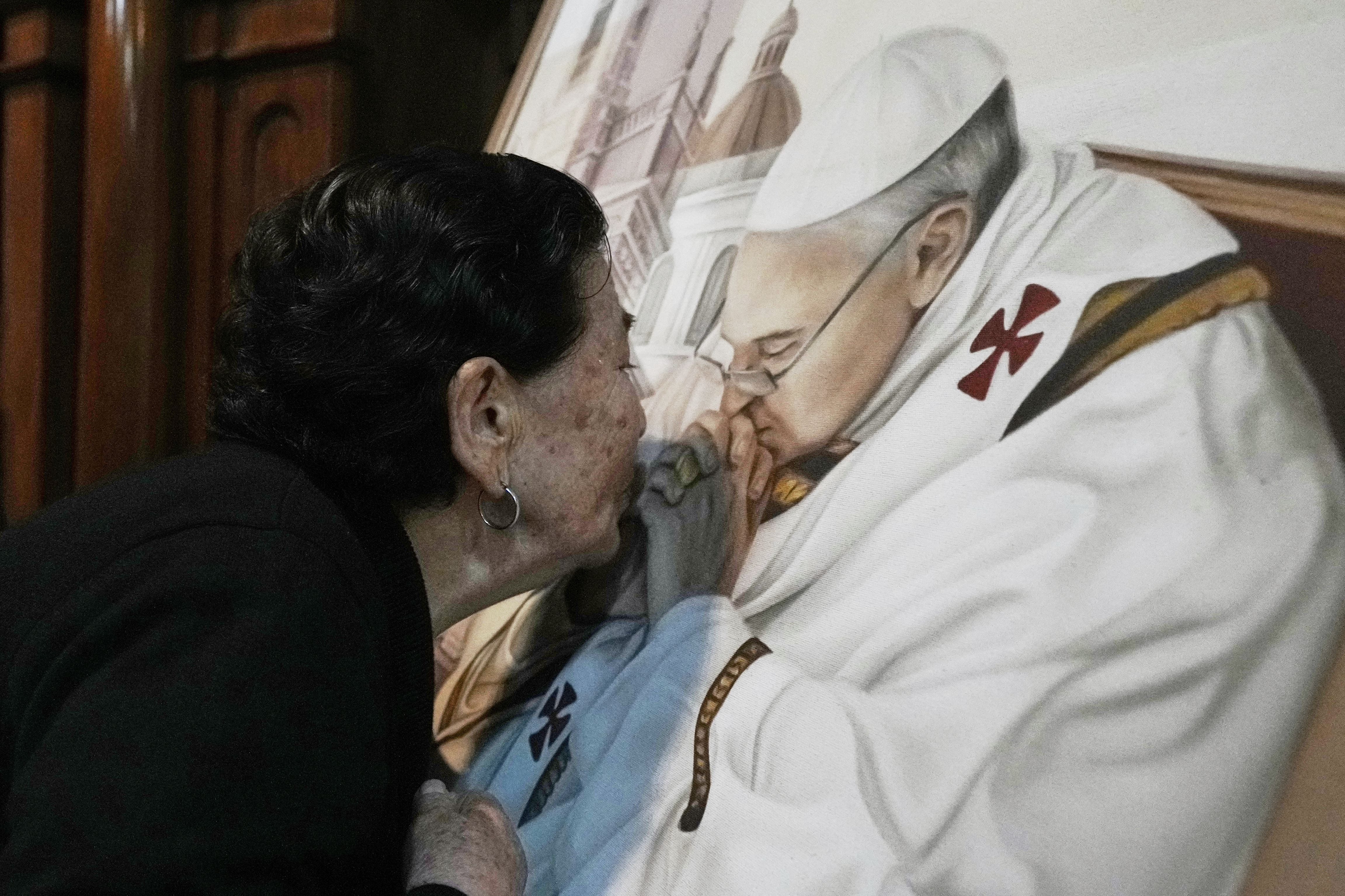 Genali Nogales kisses a painting of the late Pope Francis at the Basílica de San José de Flores, where he worshipped as a youth, in Buenos Aires, Argentina, Monday, April 21, 2025.