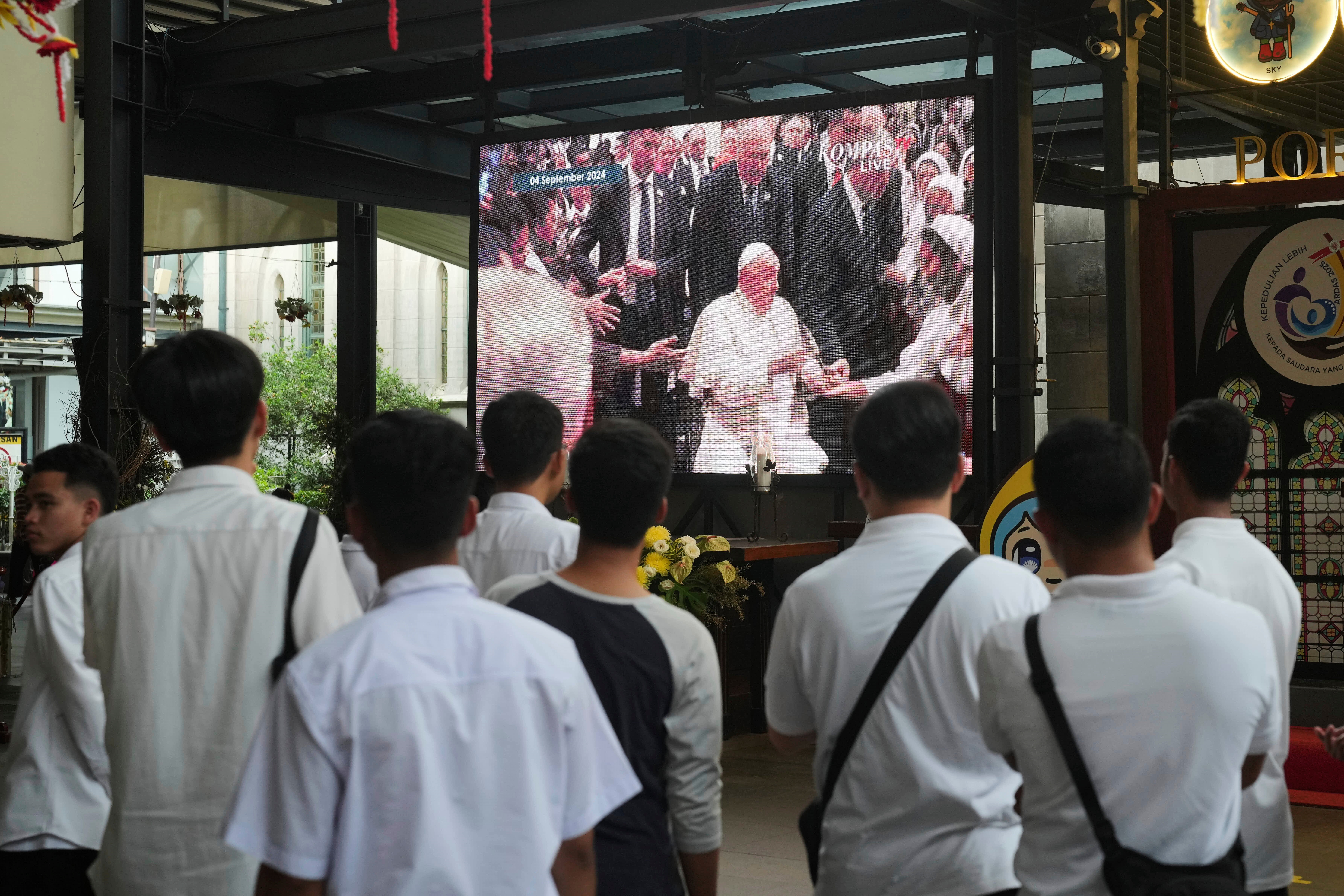 People watch a video recording of Pope Francis&#8217; 2024 visit to the Church of Our Lady of the Assumption, in Jakarta, Indonesia, Monday, April 21, 2025.