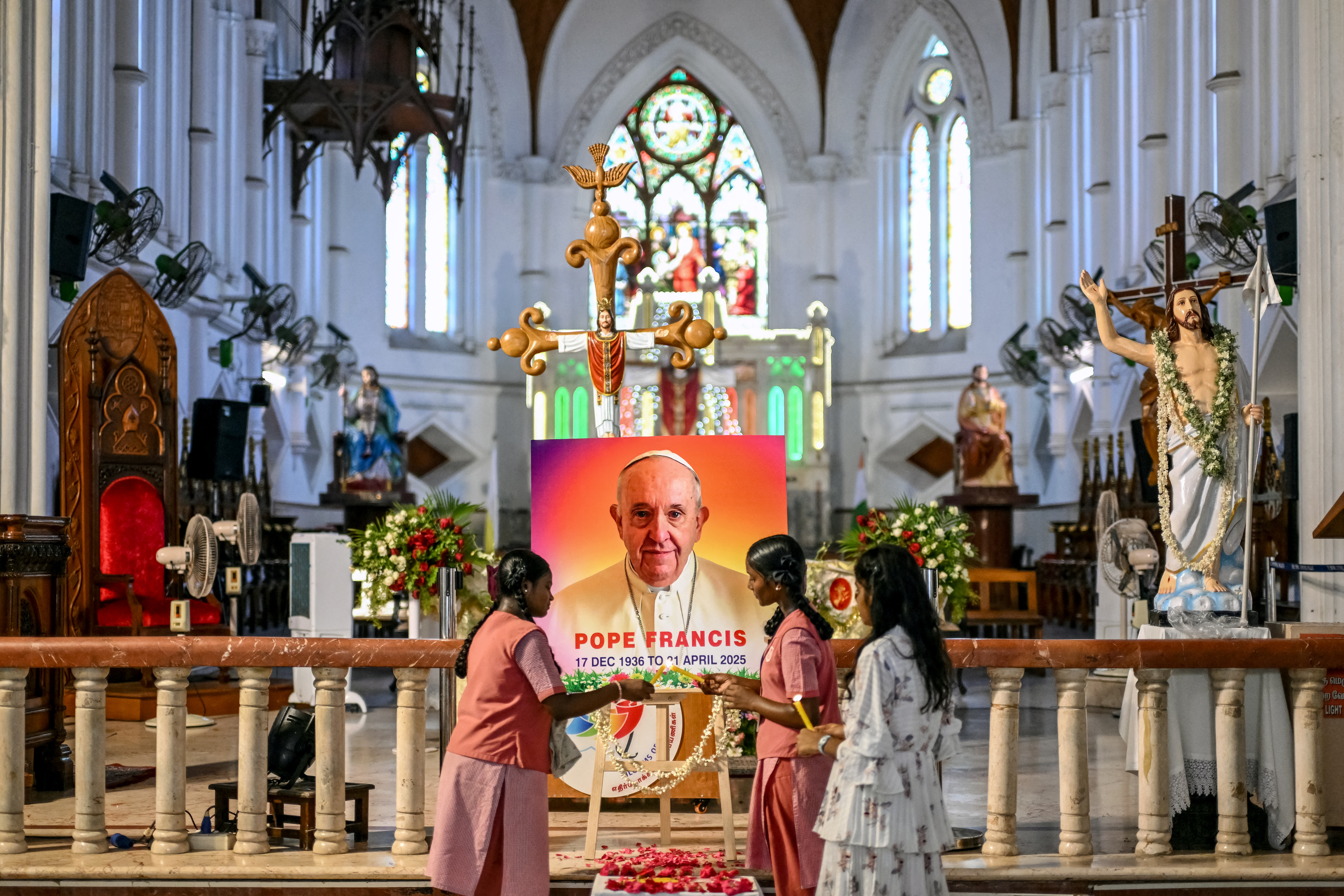 People pray in front of a portrait of Pope Francis at a Catholic church in Chennai, India on April 21, 2025, following the news of his death.