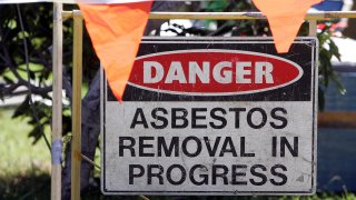 A sign reading 'Danger: Asbestos removal in progress' outside a Kiama house, 13