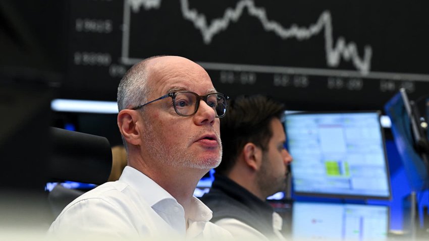 On the trading floor of the Frankfurt Stock Exchange, traders watch their monitors in front of the display board showing the Dax curve on April 9, 2025.