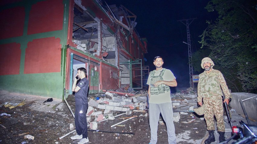 Security force officials stand outside a damaged building at a site of a suspected Indian missile attack near Muzaffarabad, the capital of Pakistan controlled Kashmir, in Wednesday, May 7, 2025.