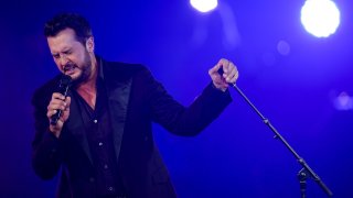 Luke Bryan singing with microphone in hand.