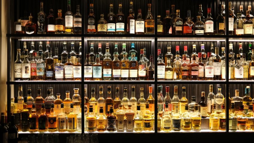 Various whiskey bottles on shelves in a bar.
