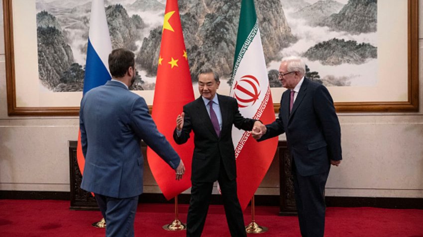 TOPSHOT – China’s Foreign Minister Wang Yi (C) gestures as he welcomes Russia’s Deputy Foreign Minister Sergey Ryabkov (R) and Iran’s Deputy Foreign Minister Kazeem Gharibabadi before a meeting regarding the Iranian nuclear issue at the Diaoyutai State Guesthouse in Beijing on March 14, 2025.