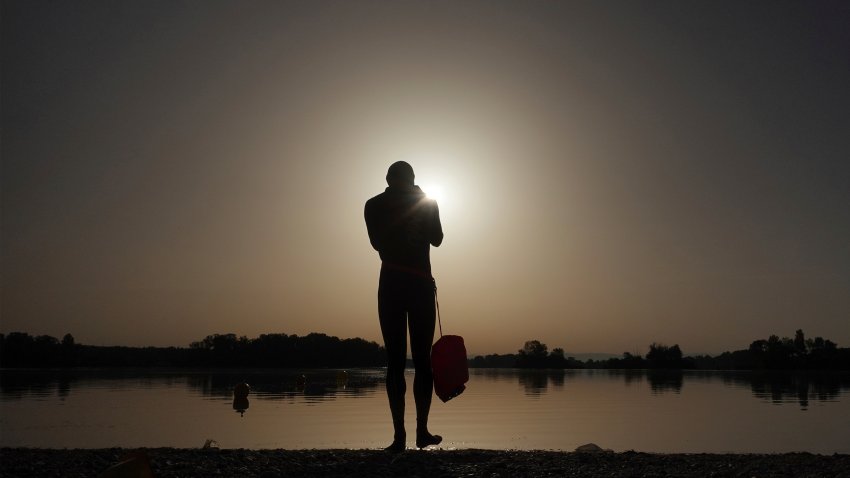 A man prepares to enter the water as the sun rises above the Miribel lake