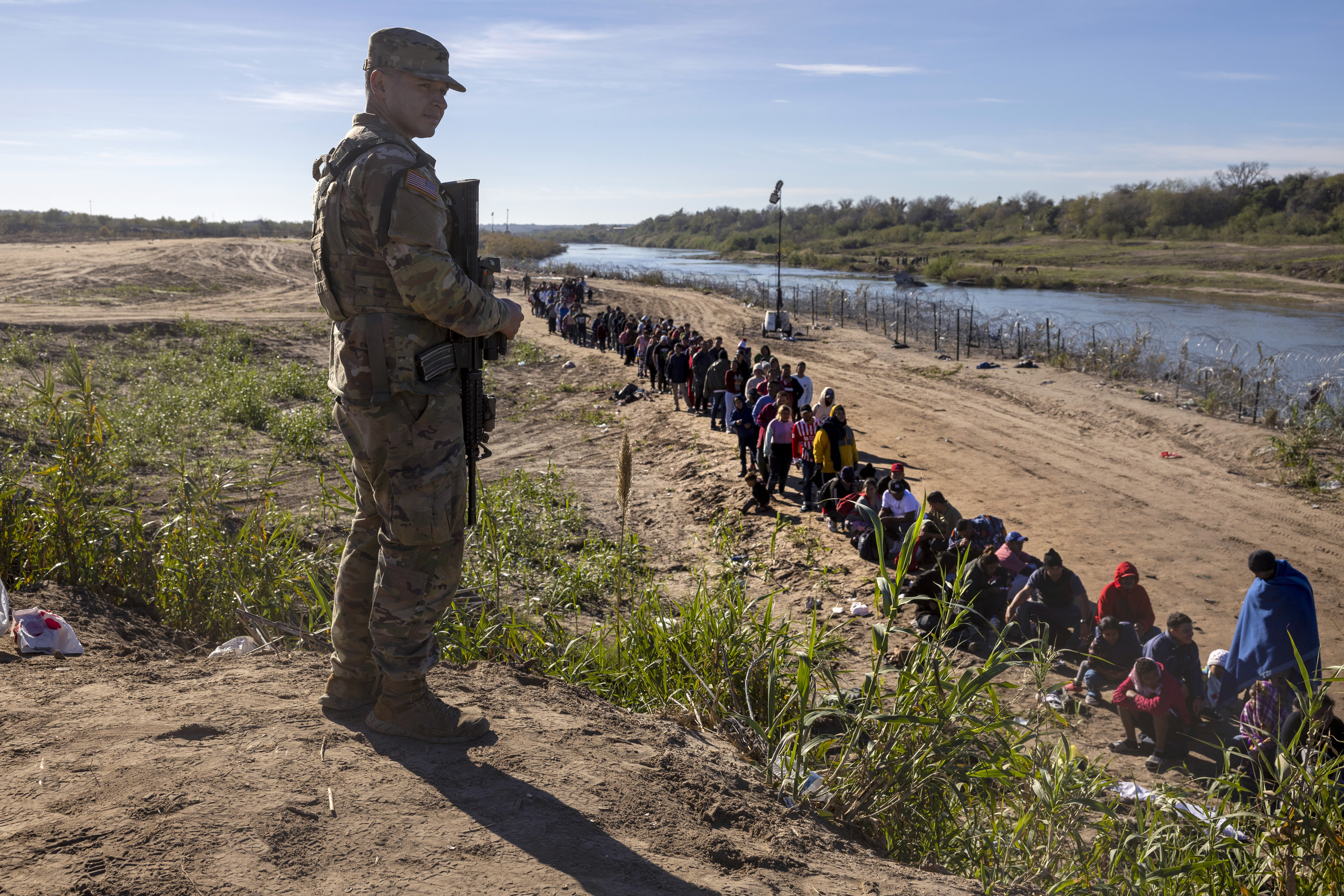 A Texas National Guard soldier watches over a group of more than 1,000 migrants