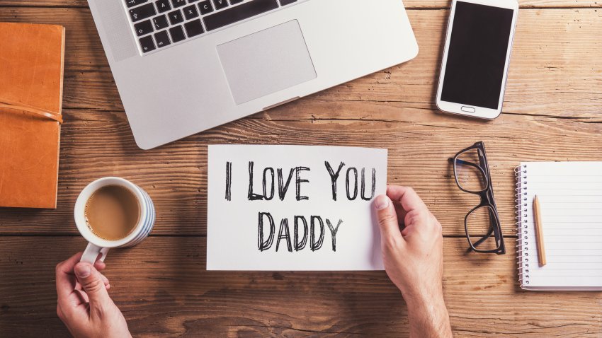 I love you daddy sign on desk with laptop, phone, notebook, coffee and glasses
