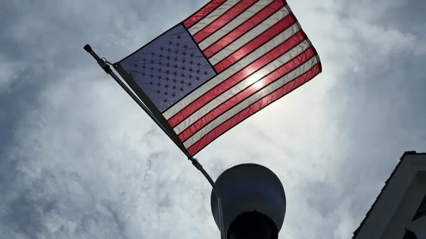 An American flag waving in front of a mostly blue sky.