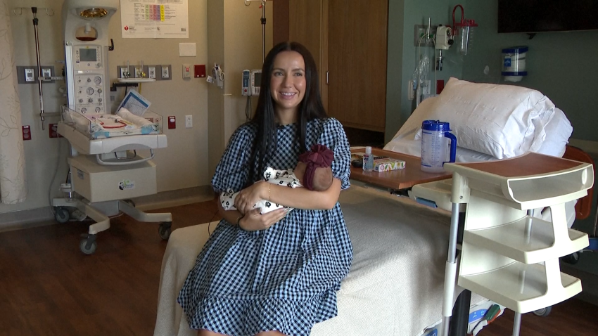 New mom holds newborn baby in hospital room