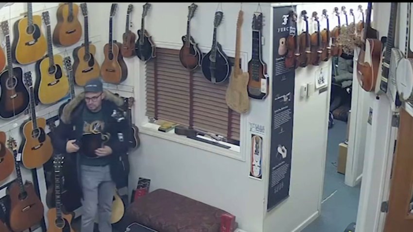 Man appears to stuff mandolins into his large winter coat, caught on camera at a New Jersey music store.