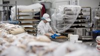 An employee slices cake inside the bakery of a Costco