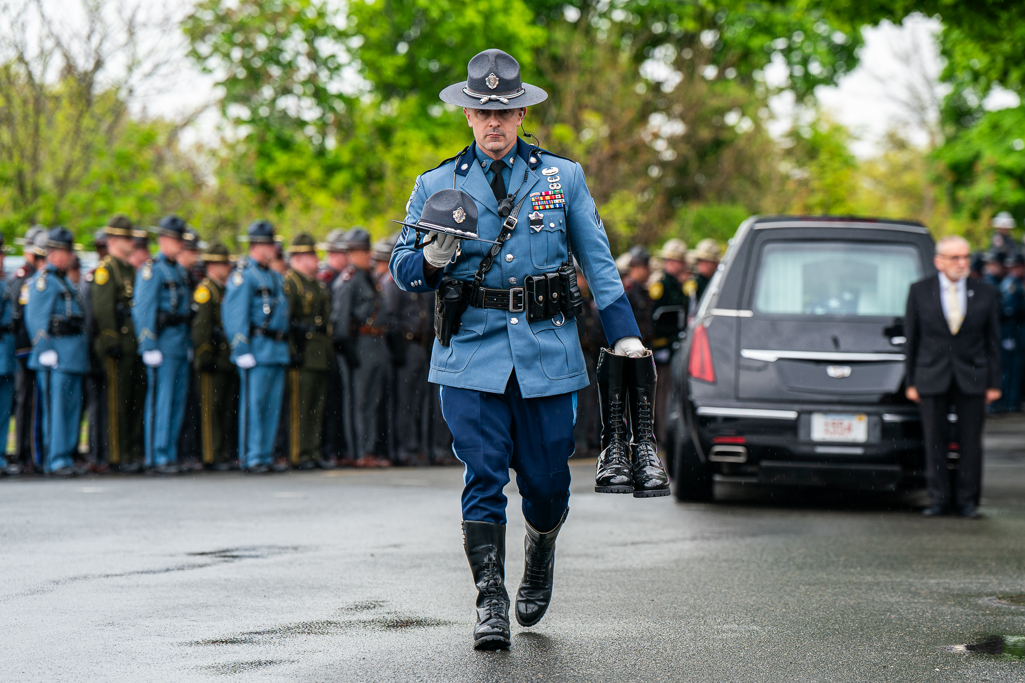 A Massachusetts State Trooper carries Trooper Kevin Trainor's hat and boots during Trainor's funeral service outside of St. James Church in Salem, Massachusetts, on Wednesday, May 13, 2026.