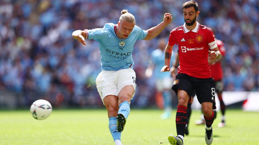 Erling Haaland of Manchester City shoots whilst under pressure from Bruno Fernandes of Manchester United.